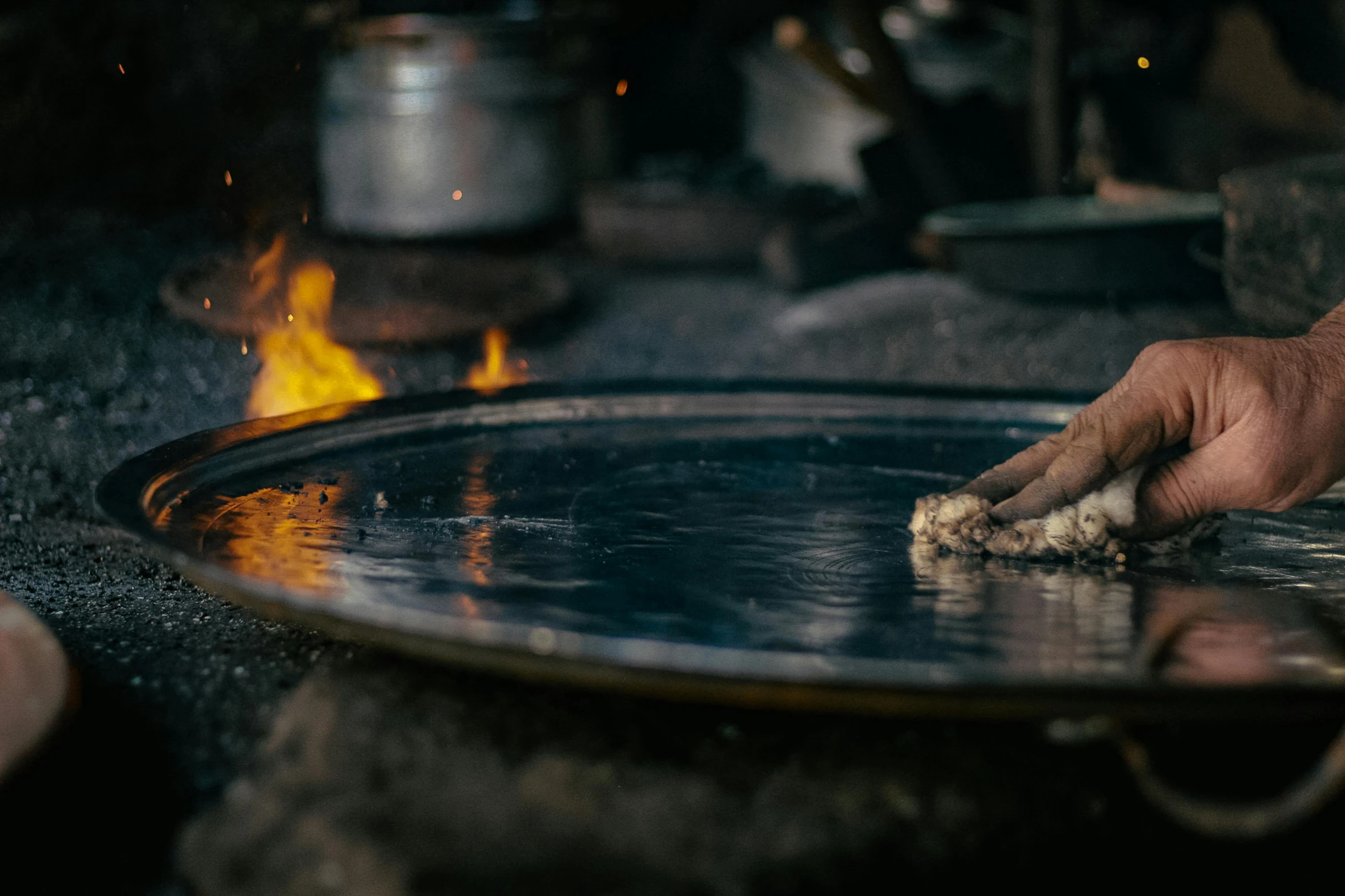 a person holding their hand near a pan on fire