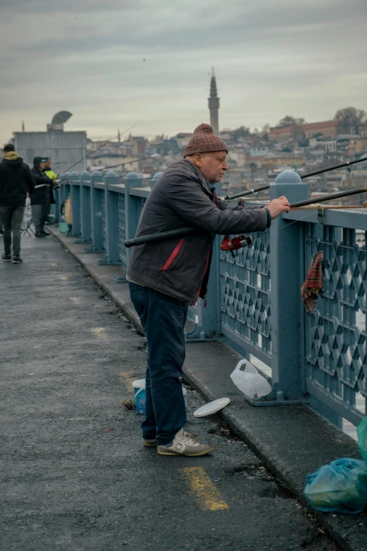 a man holding onto a fishing rod on the edge of a bridge