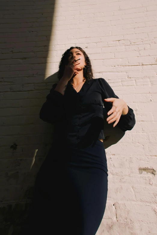 a woman poses in front of a brick wall