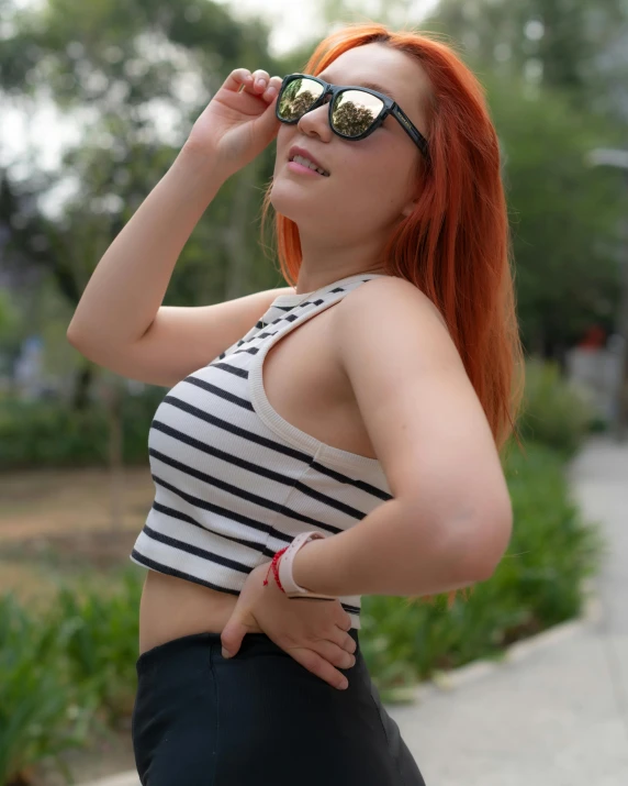 a woman with red hair wearing sunglasses and standing outside