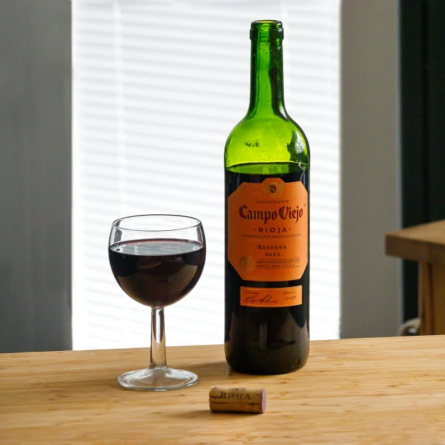 a bottle of wine, next to a wine glass on a table