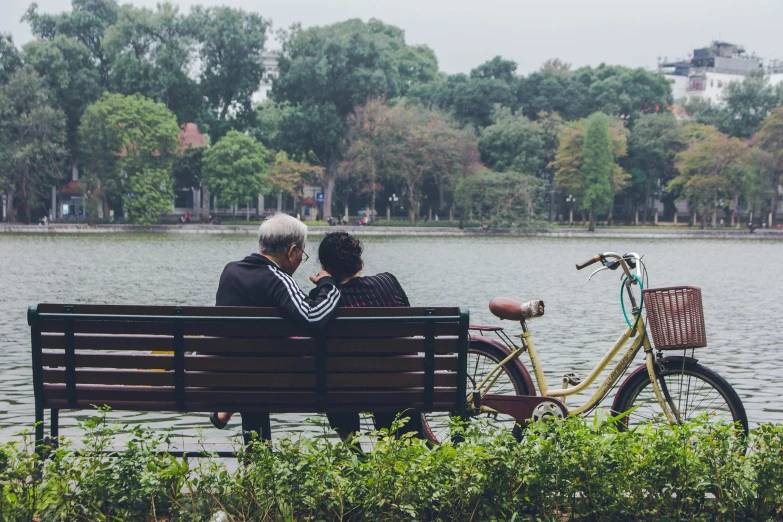 a man and woman sitting on a bench next to a bicycle