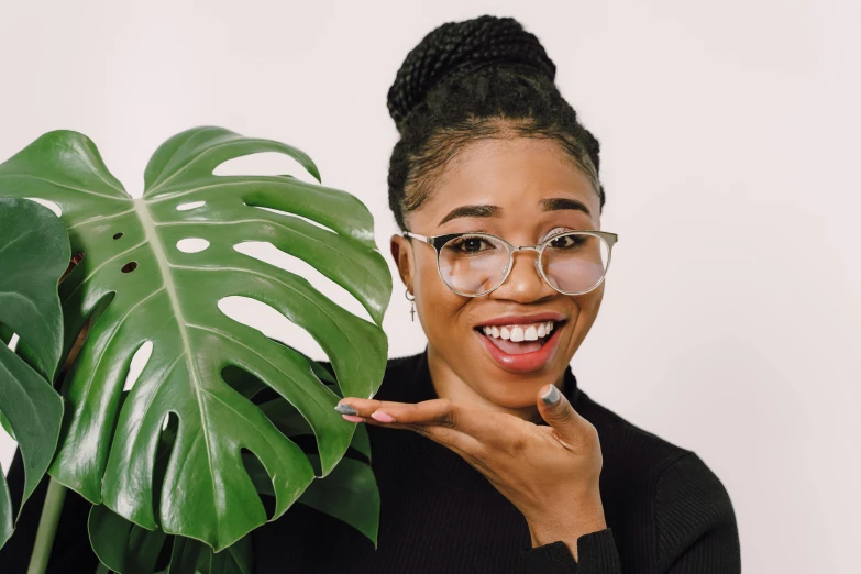 a woman in glasses is making a funny face and holding up a plant