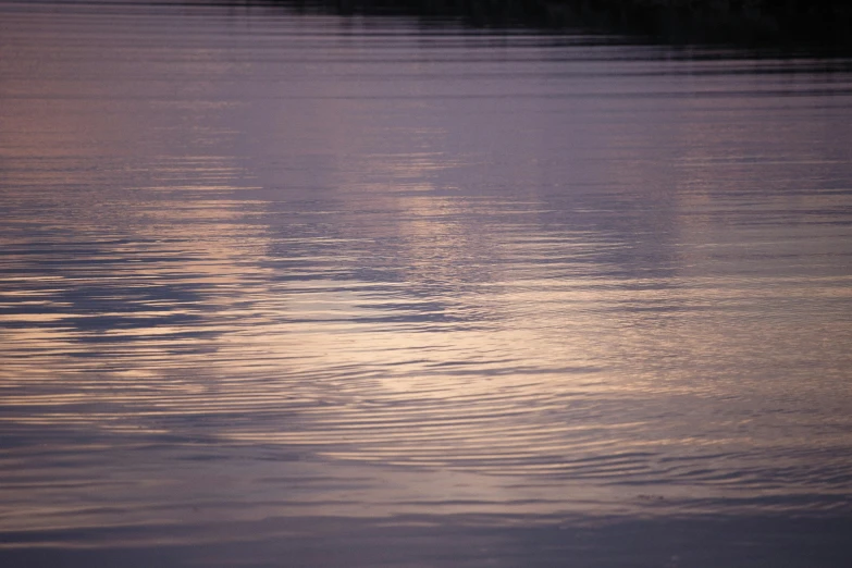 the sun rising on the water and reflects the clouds