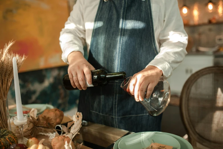 a man standing over a table pouring wine into a glass