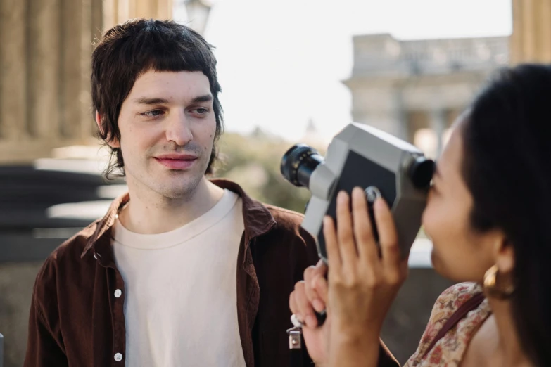 a man in a jacket holding a camera next to a woman