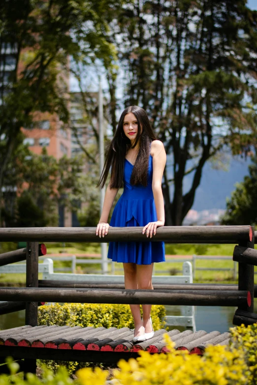 a beautiful young woman standing on top of a wooden deck