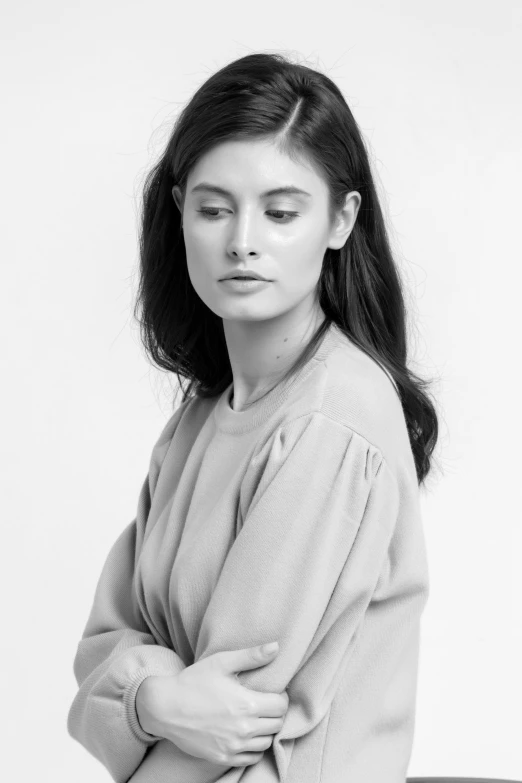 a woman sitting next to a white wall