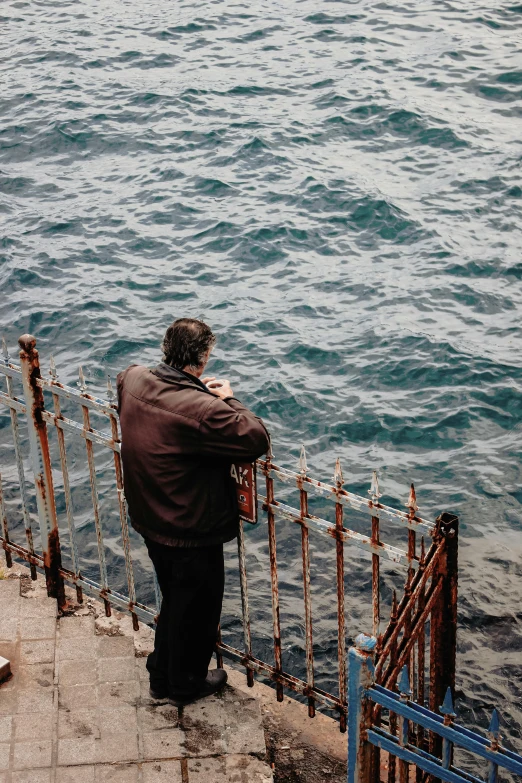 a man is standing near the water looking at the sea