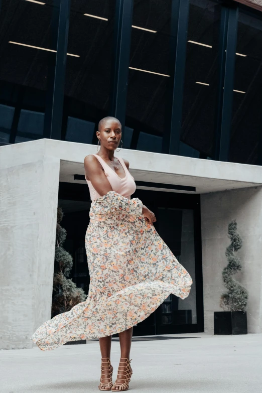 the woman in floral print dress is walking across a cement building