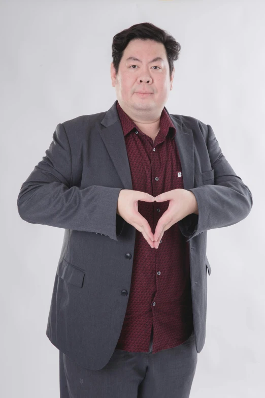 man in suit making a heart shape with hands