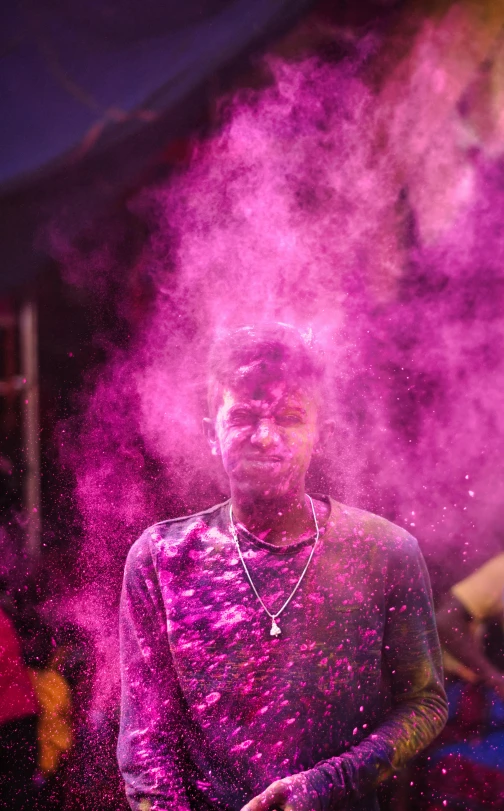 man standing outside in the middle of the night, making pink and purple smoke