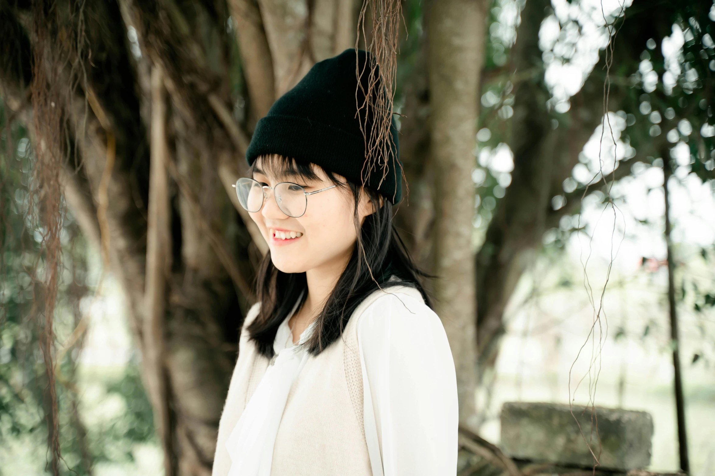 a girl with glasses and a hat in a forest