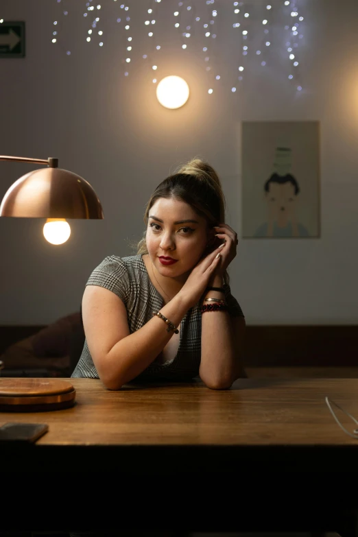 a woman sitting at a wooden desk with a light on