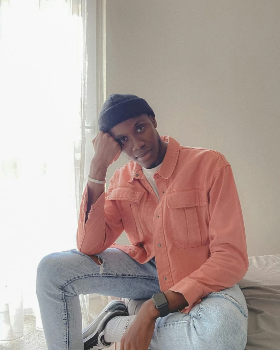 a man sitting on a bed holding a hat on his head