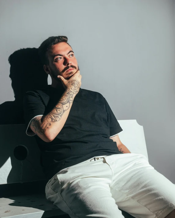 a man poses for a portrait in white denim jeans and black tee shirt