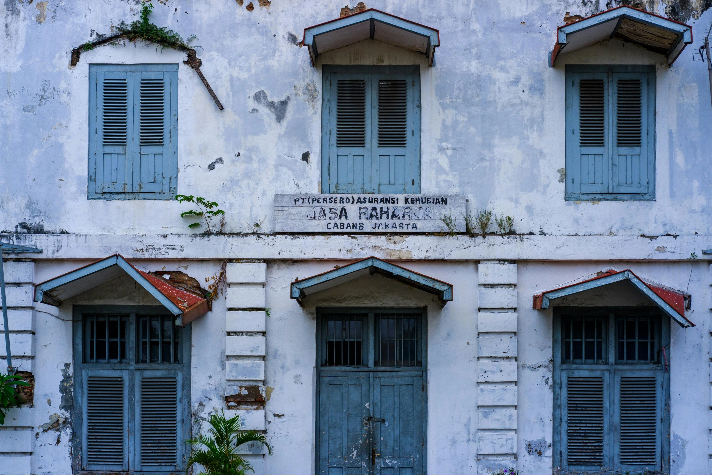 a white building with three windows and three blue shutters