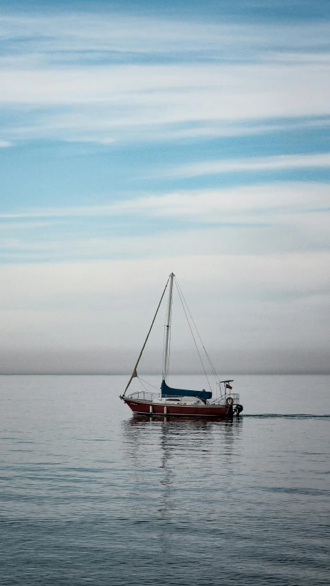 a small boat floating on top of a lake under a blue cloudy sky