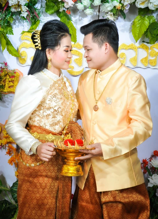 couple dressed in traditional thai costumes posing with food