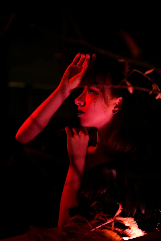 a young lady sits on a chair holding her hands in the air with her hands, while staring into the distance