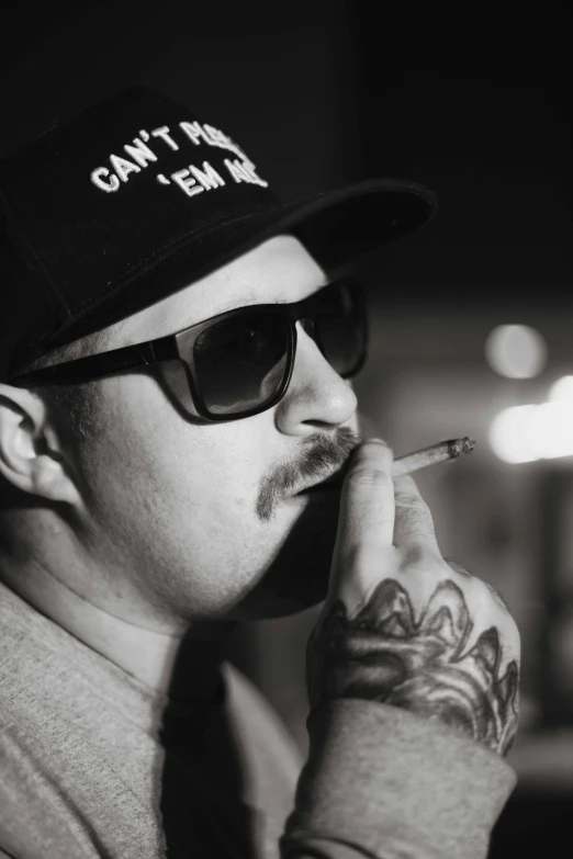 a man with glasses and a cap smoking a cigarette