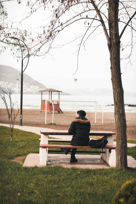 a man sitting on a bench overlooking the ocean