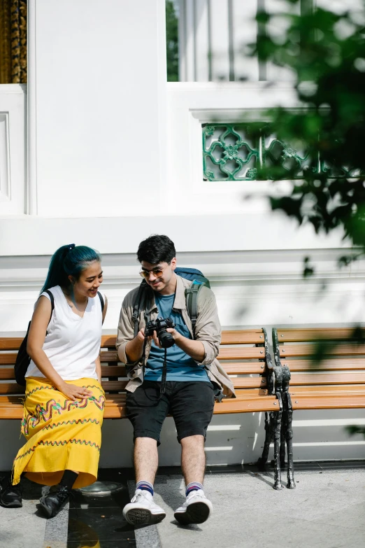 man and woman sitting on bench while using cell phone