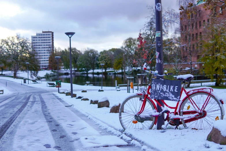 a bicycle  to a pole in the snow