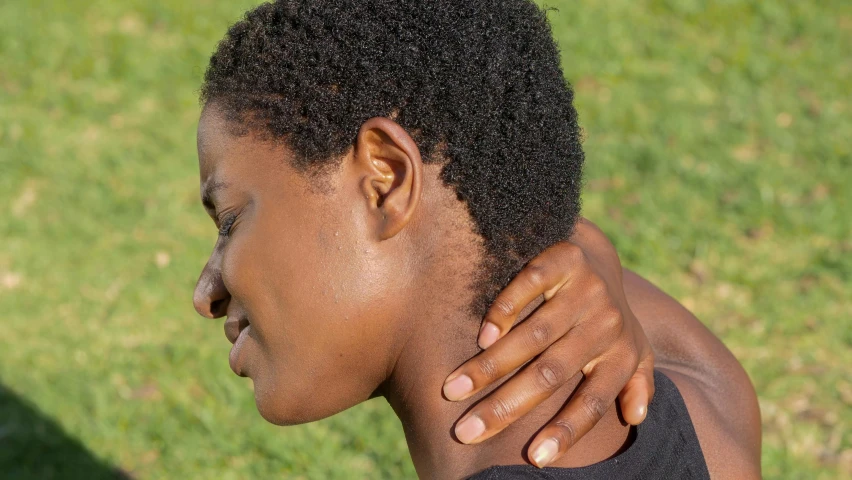 a woman holds her neck open while outside