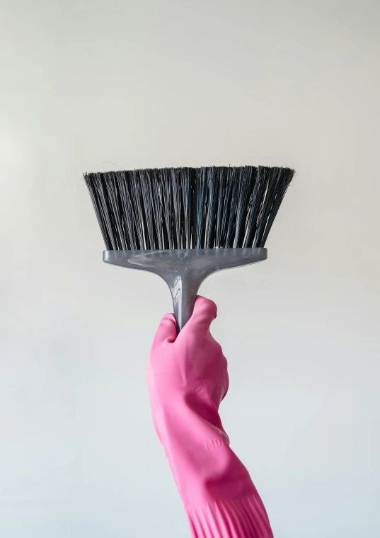 a person holds a pink brush to clean it