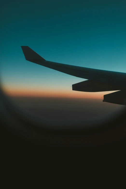 the window is closed to show a view of an airplane wing and it's wingtip