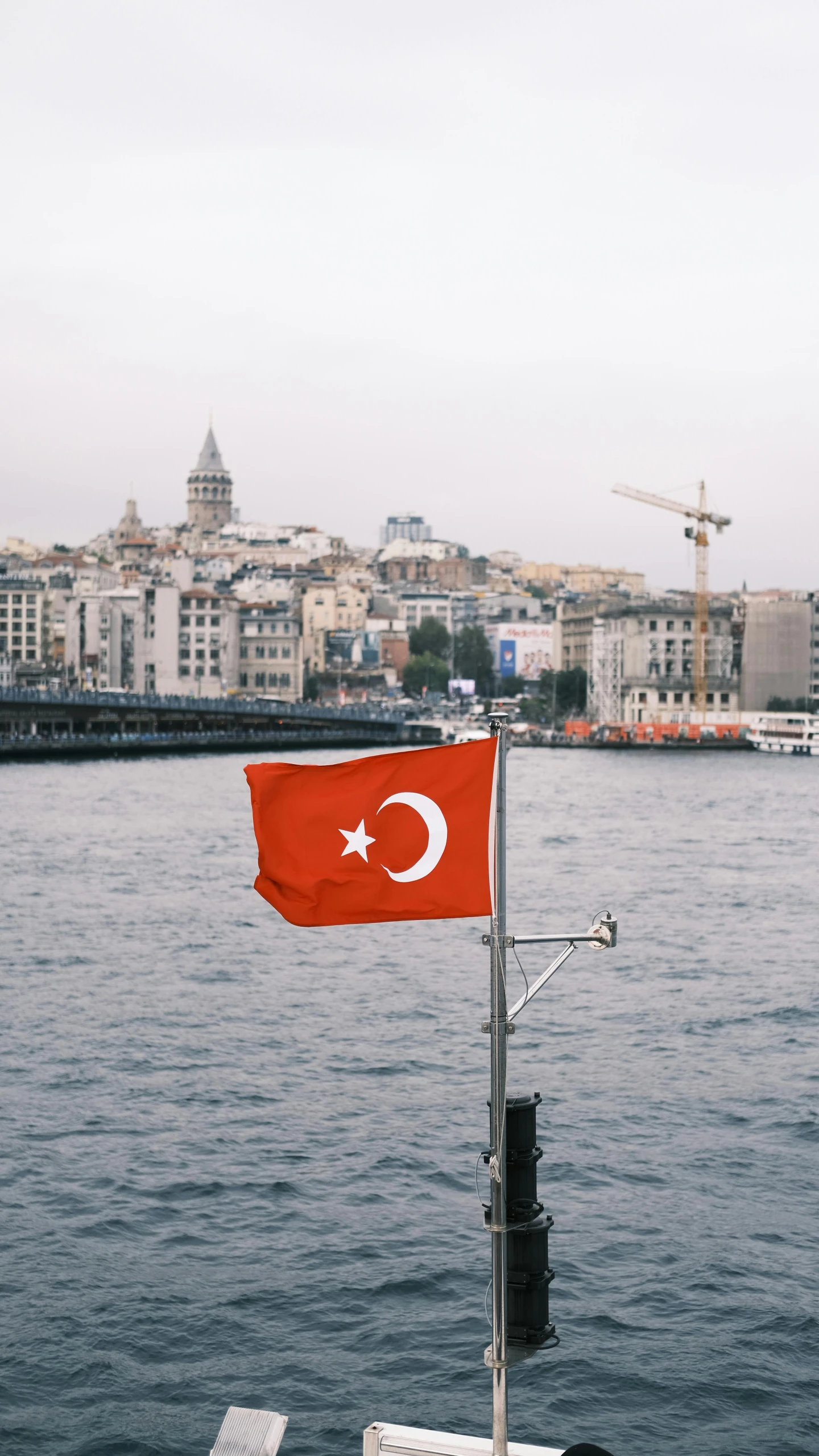 a turkish flag is waving in the wind along the water