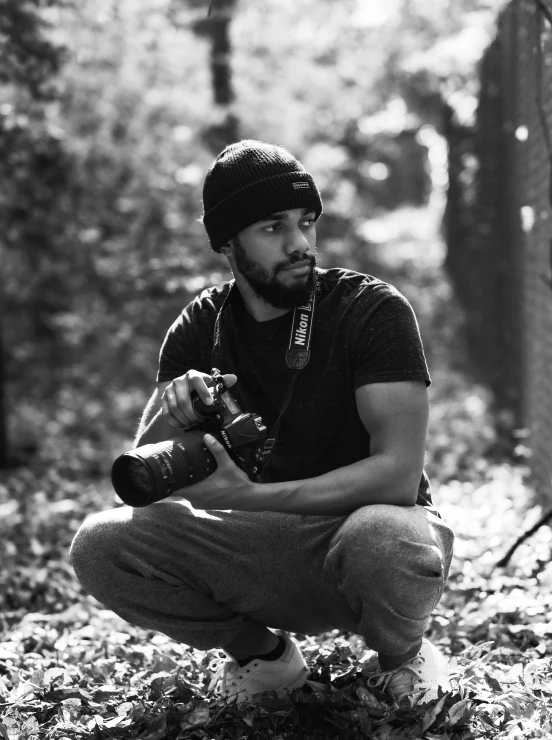 a man is sitting in the woods holding a camera