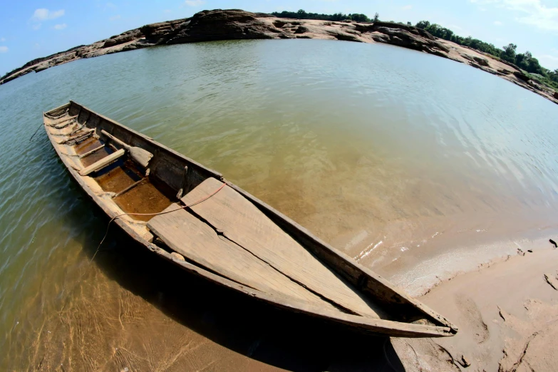 an old rowboat rests on the bank of a lake