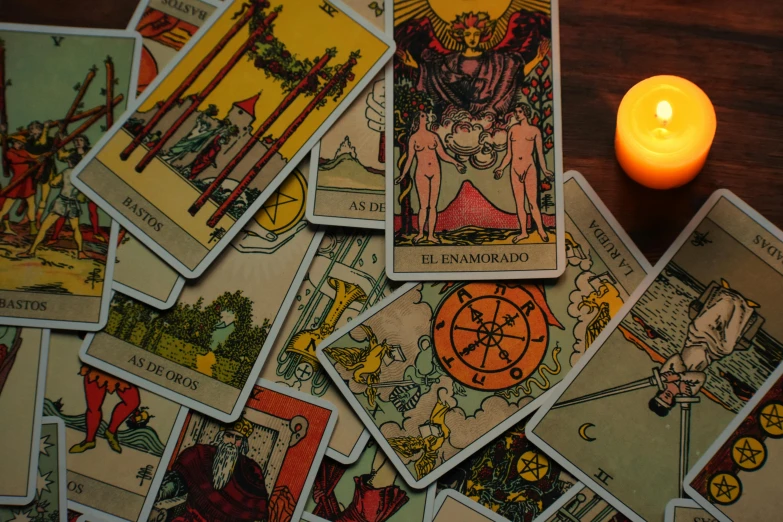 various tarot cards sitting next to a candle