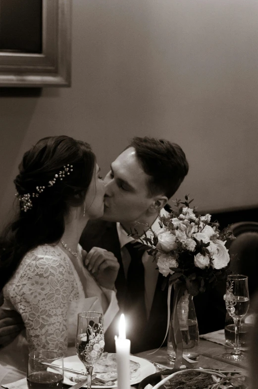 a couple is kissing while sitting down at the dinner table