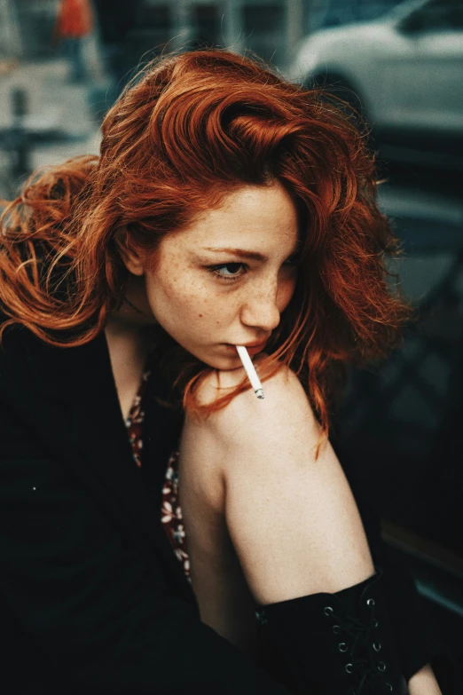 woman with red hair smoking a cigarette and looking at the camera