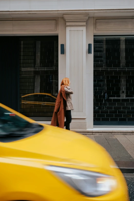 a woman standing on a street corner near a taxi