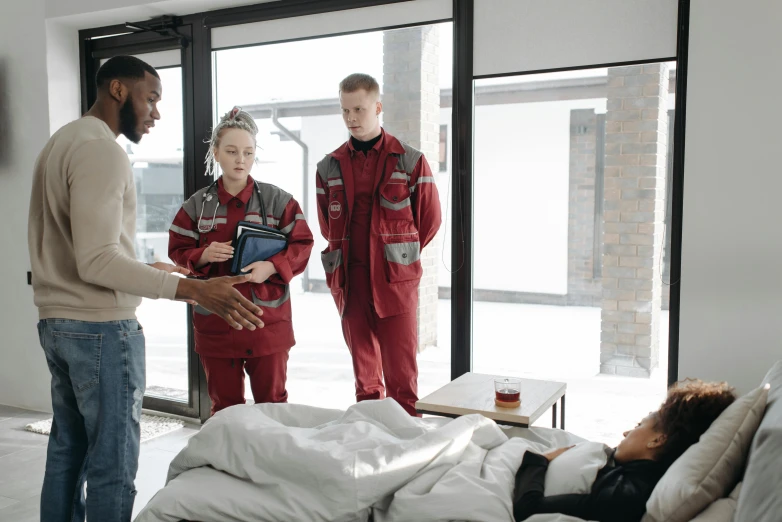 a man and two women in matching red workwear talking in front of a sliding glass door