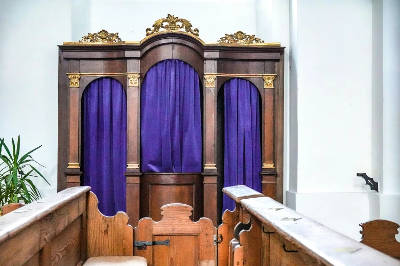 a church pulpit with purple curtains next to a bench