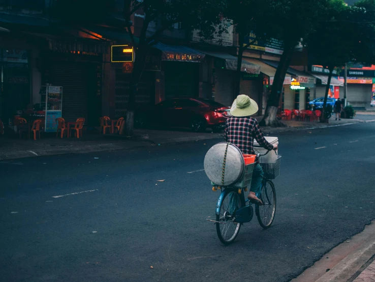 man riding bicycle down the road with white bags on basket