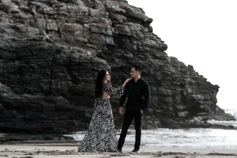 a man and a woman are on the beach, holding hands