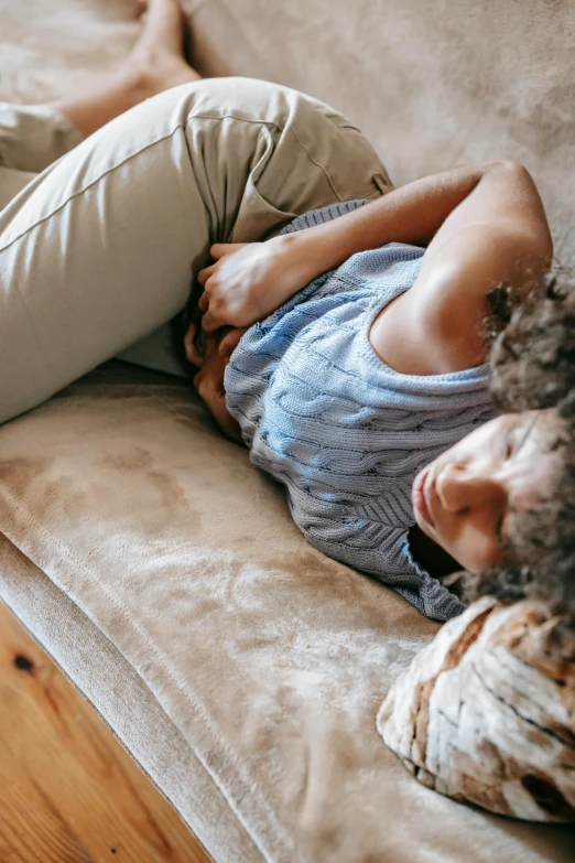 a woman wearing a sweater lays on a sofa