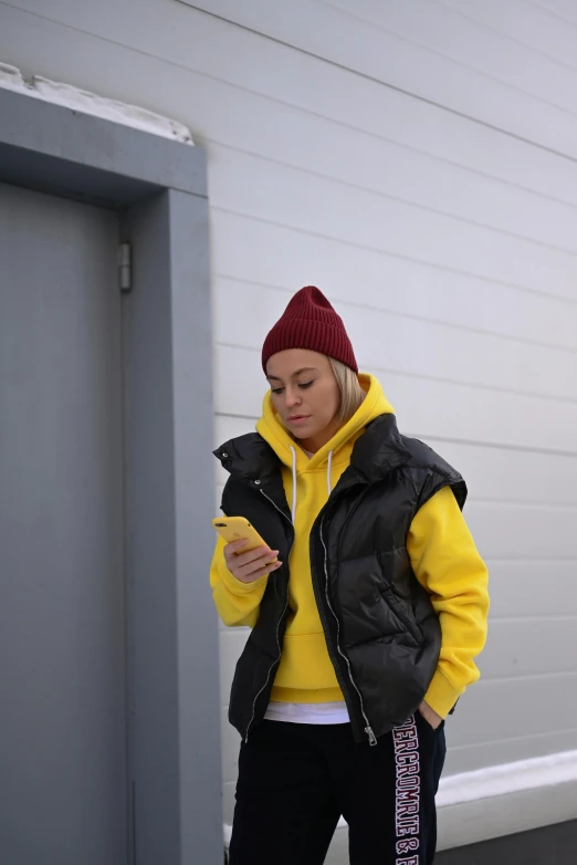 a girl in a yellow jacket checking her cell phone