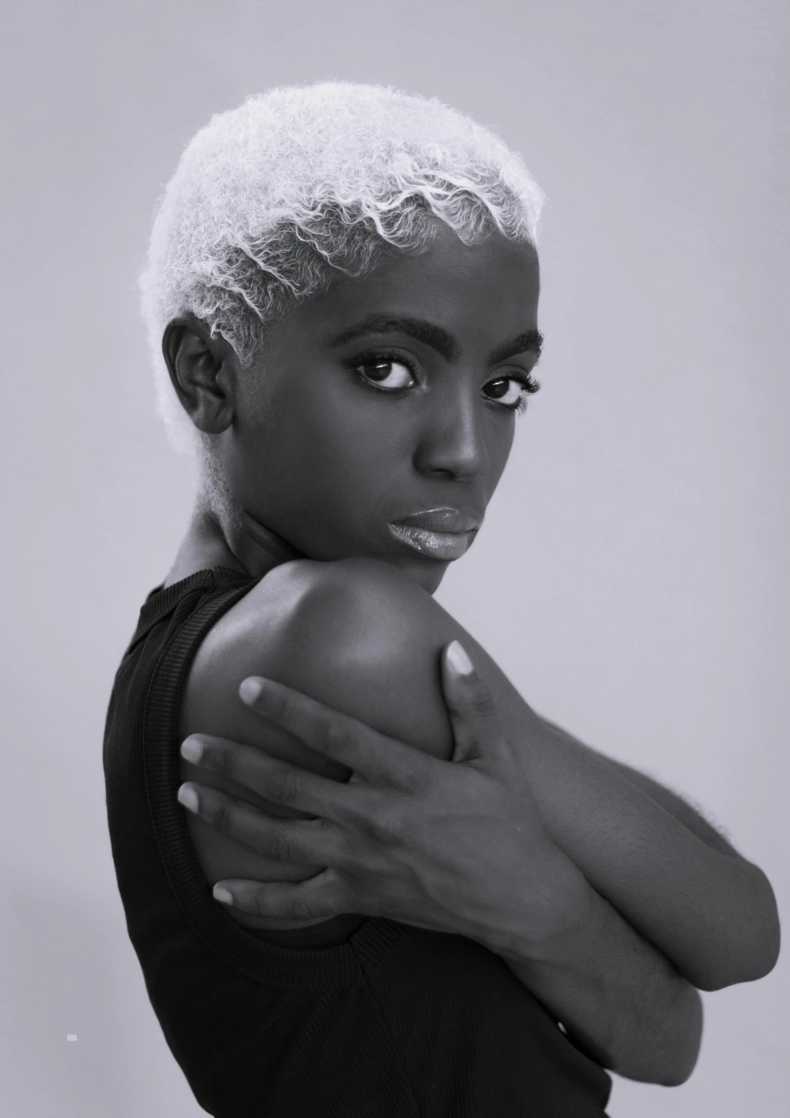 a black and white po of a woman with her hands folded around her shoulder