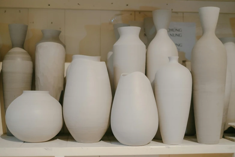 several large white vases stacked on a shelf