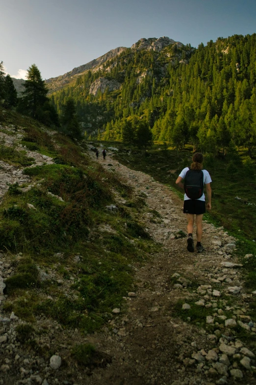 man in hiking gear walking up a rocky trail towards a mountain