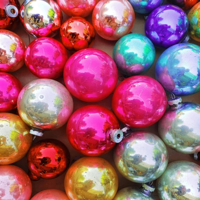 a large group of shiny colored christmas ornaments