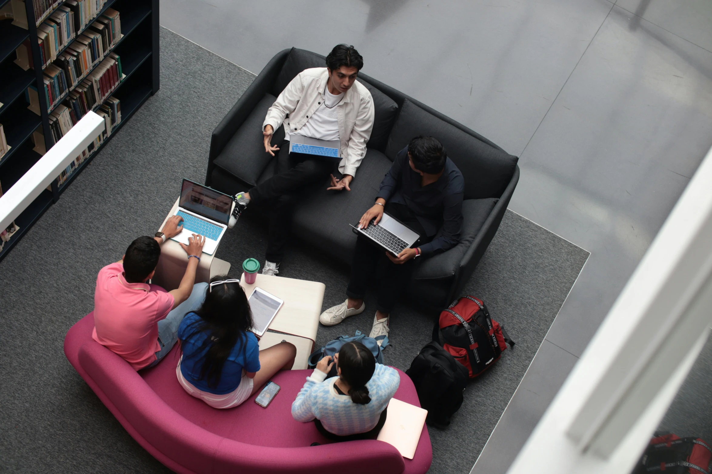 two men and two women sitting on a sofa together looking at laptops