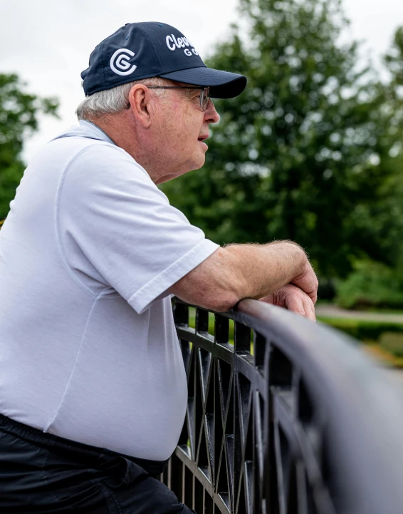 a man leaning on the metal rail of a fence